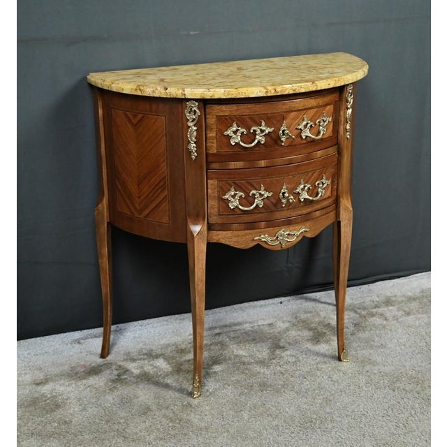 This charming little half-moon commode embodies the delicate elegance of the Louis XV-Louis XVI Transition style, a blend...