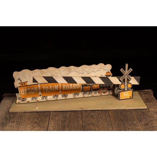 Vintage mechanical point-of-sale display advertising Upson Train Board, a lightweight fiberboard marketed for use as...
