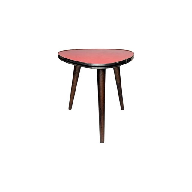 Authentic vintage side table from the mid-20th century, with a rounded triangular top, made of orange formica with a...