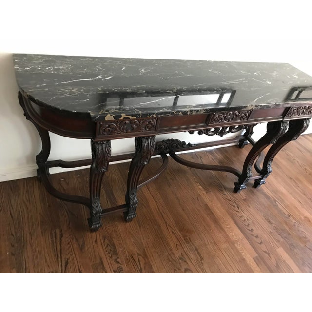 This is a beautiful black onyx marble credenza table, circa 1920. The piece features carved dark mahogany, with one large...