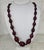 This necklace features a classic graduated bead design in a rich burgundy hue. It is an elegant addition to formal or...
