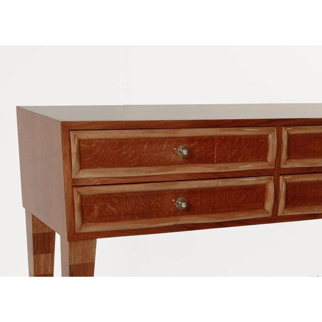 This console table has a slightly angled oak body holding four drawers fitted with undulating maple moldings and glass...