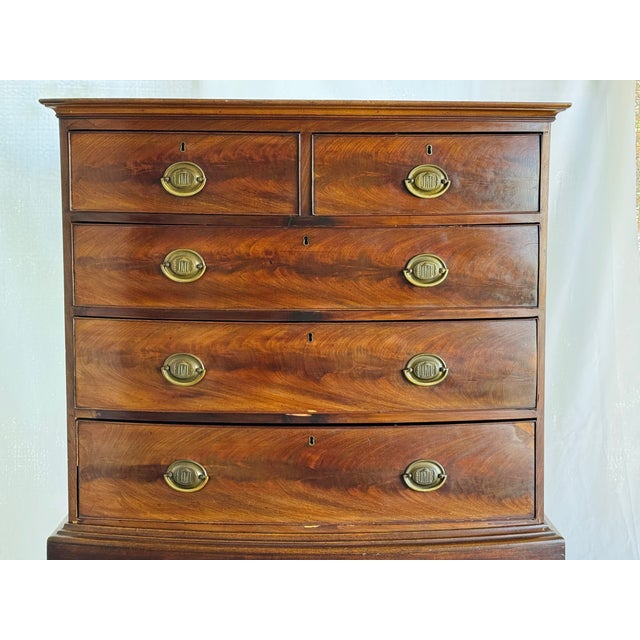 A George III style mahogany bow front chest of drawers on a later stand. Drawer fronts with replacement brass pulls....