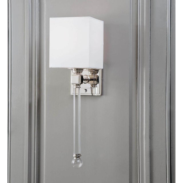 The modern silhouette and suspended cut crystal stem with clear ball finial of this sleek sconce emotes luxurious style. A...