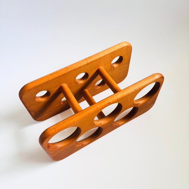 A vintage mid century teak 5 bottle wine rack. One side has large holes for the bases of the bottles with the other side...