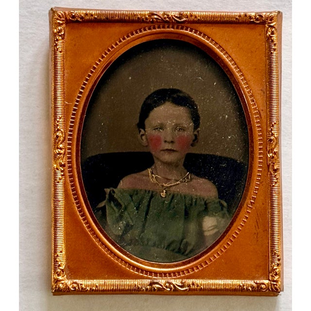 This antique photograph captures a beautiful portrait of a young Victorian girl. The image is hand-tinted and features a...