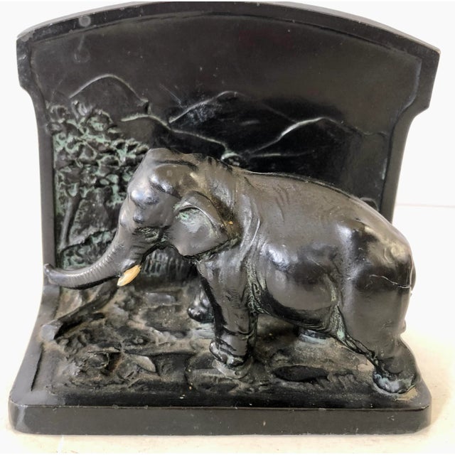 These heavy metal bookends each have an elephant mounted on them, strolling through their terrain.