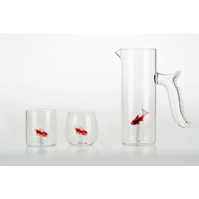 Set of 4 rounded shape mouth blown transparent glasses. Inside each, a small colored (blu or red) fish, swims as in the...
