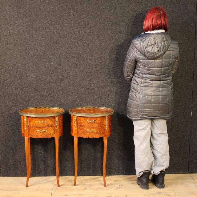 A pair of French bedside tables from the mid-20th century. Oval-shaped furniture inlaid with floral decorations in...