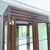 This vintage campaign-style curio cabinet pairs a tall, slender silhouette with rich dark wood and warm brass accents....
