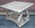 A Mid Century distressed white washed rectangular two tier side table with scroll details. Measures 28" in width, 24" in...