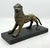 A cast bronze lion figure mounted on a black rectangular base, depicted in a dynamic stance with stylized detailing,...