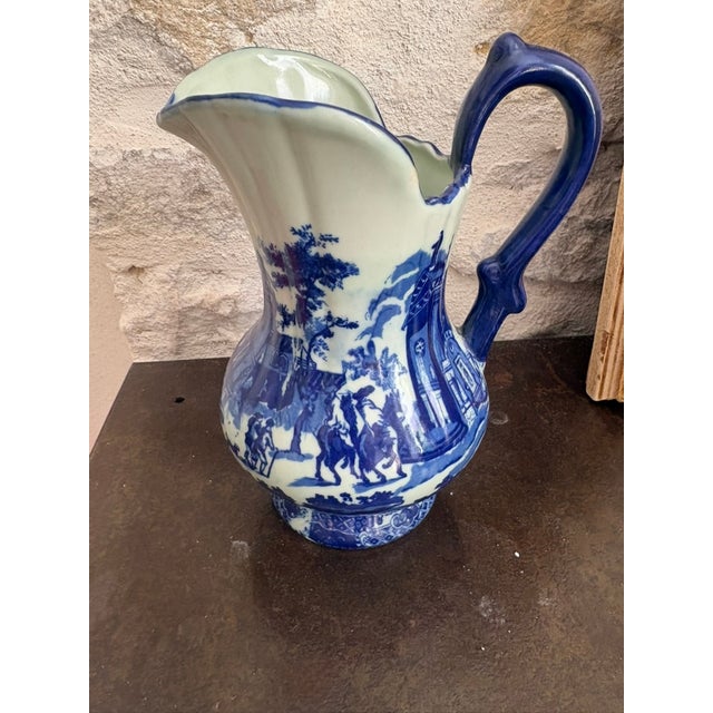 A blue and white transferware pitcher marked "Victoria Ware Ironstone" to the base, with the royal arms mark used by this...