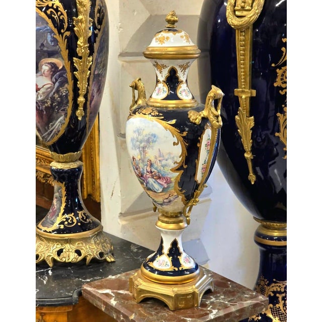 Elevate your décor with this exquisite hand-painted porcelain urn vase, featuring a romantic classical scene framed by...