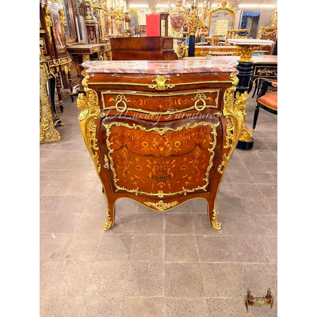 A richly detailed French Louis XVstyle bombé commode, featuring a beautifully curved silhouette, warm wood tones,...