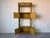 Charming vintage bent rattan bookcase featuring a warm mustard yellow finish with sculptural bamboo-style curves and...