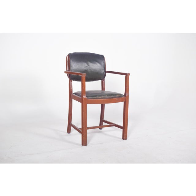 Office chair with arms. Seat and backrest upholstered in black vinyl material, fixed to the back directly to the frame....