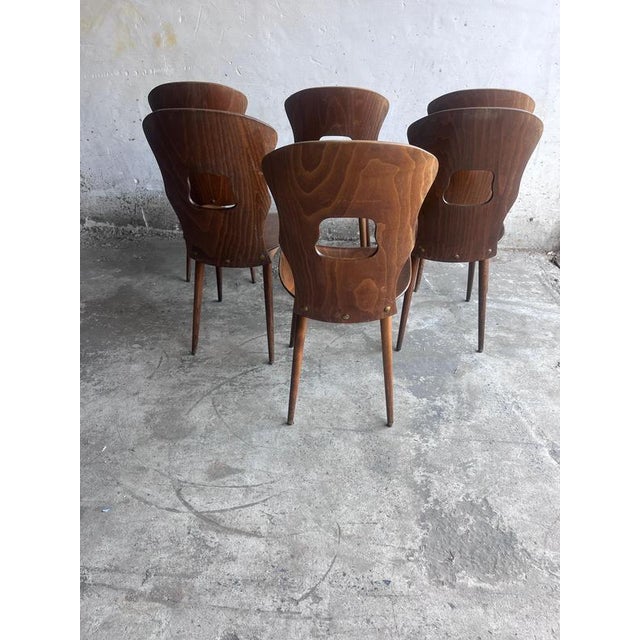 Elegant set of six vintage dining chairs by Baumann, produced in France during the 1950s. The chairs feature sculpturally...