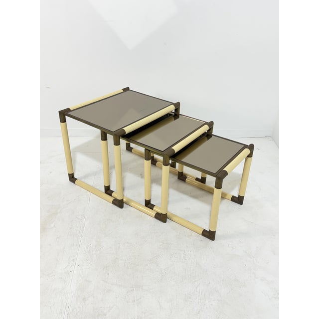 Set of 3 enameled metal and brass coffee tables in the style of Tommaso Barbi, 1970 Smoked glass tops. Good condition....