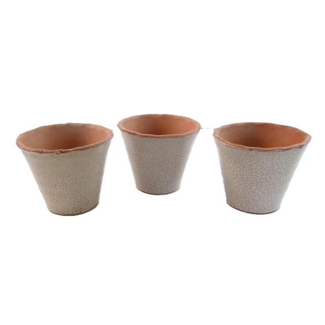 A vintage set of three clay cachepots with a pale pink crackled glaze finish. Perfect for holding small plants, small...