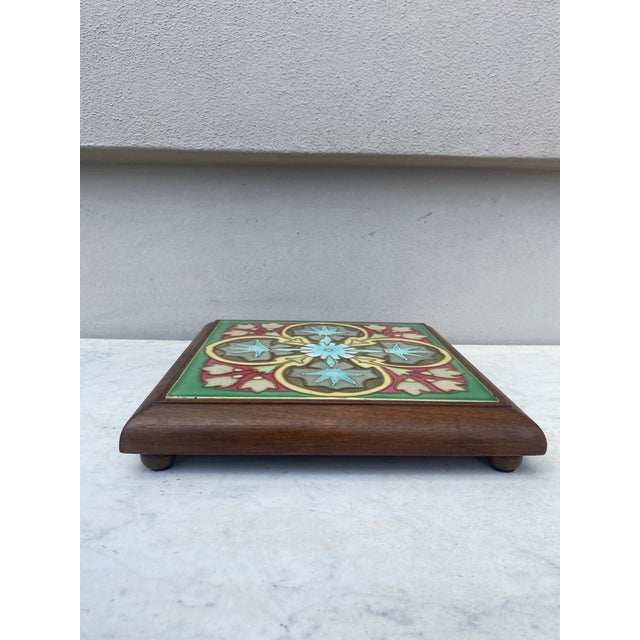 Art Nouveau Majolica trivet in a footed wood frame, circa 1900. Geometric floral pattern.