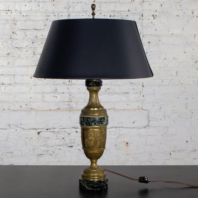 Marvelous vintage Neoclassical table lamp composed of an antiqued brass finish body with ornate embossed details, black...