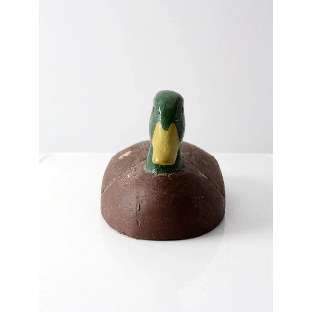 This is a vintage duck decoy. Hand-painted and crafted from cork and wood, the decoy depicts an American mallard duck.