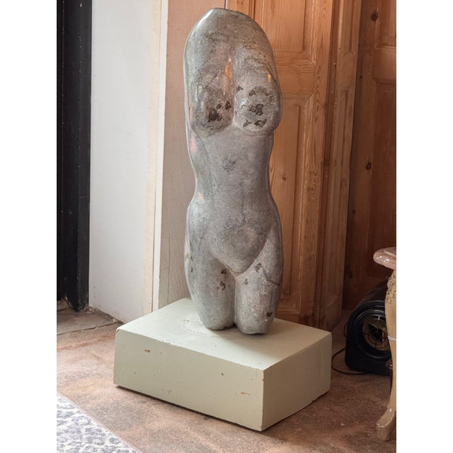 Modernist carved stone female torso with smooth, rounded forms and natural mineral markings, mounted on a painted wood base.