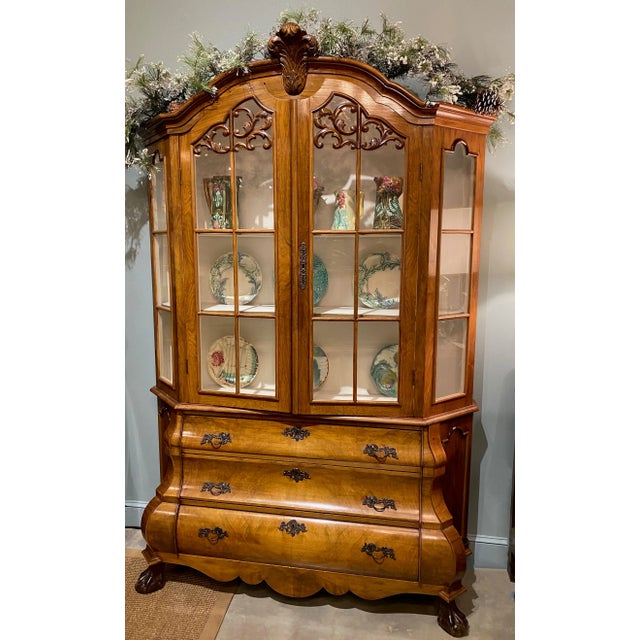An early 20th century Dutch walnut bombe breakfront with double glass doors at top and three lower drawers all with...