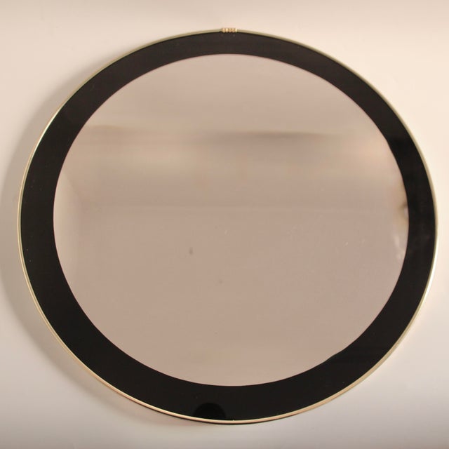 This very well-preserved 1950s wall mirror features a beautiful black border ornament framing the mirror surface and metal...