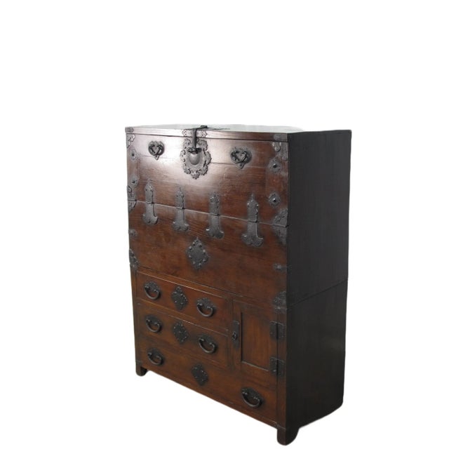 This dark brown Korean antique cabinet consists of two separate parts. The top cabinet has a large compartment with 3...
