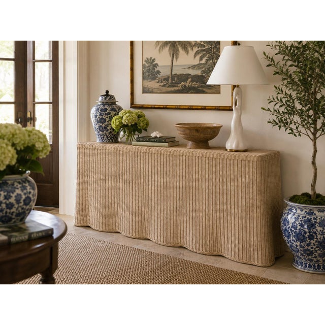 A chic wicker rattan console table with a beautifully scalloped silhouette and tightly woven surface. The piece has the...