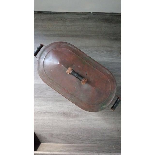 This is an antique cooper wash tub with a matching oval lid and wooden handles. It was placed on a wood or coal cookstove...