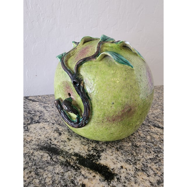 A generously sized Chinese altar fruit modeled as a ripening peach, blushing from soft green to deep raspberry pink at the...