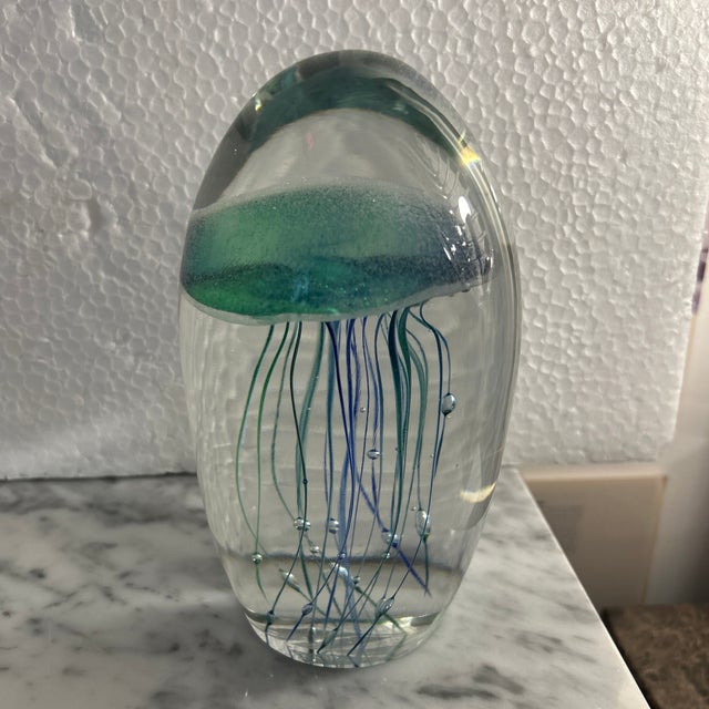 Very thick glass sculpture or paperweight with a green/ blue jellyfish design inside with bubble inclusions. The colors...