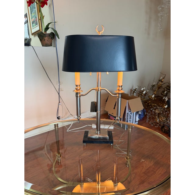 A Haig table lamp featuring a solid brass frame finished in satin nickel with a black marble base on elevated nickel feet....