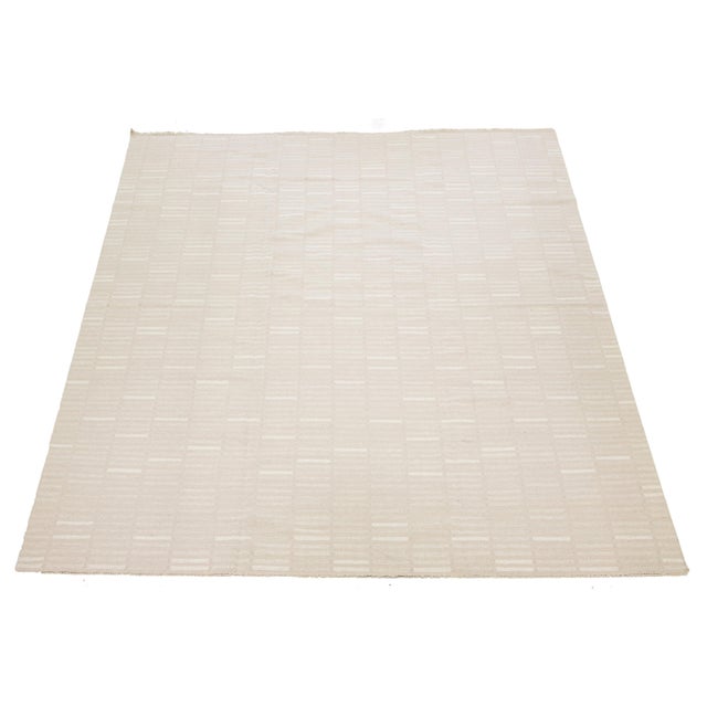 This rug features an organic modern design characterized by a wool Kilim flatweave. It displays a geometric pattern in...