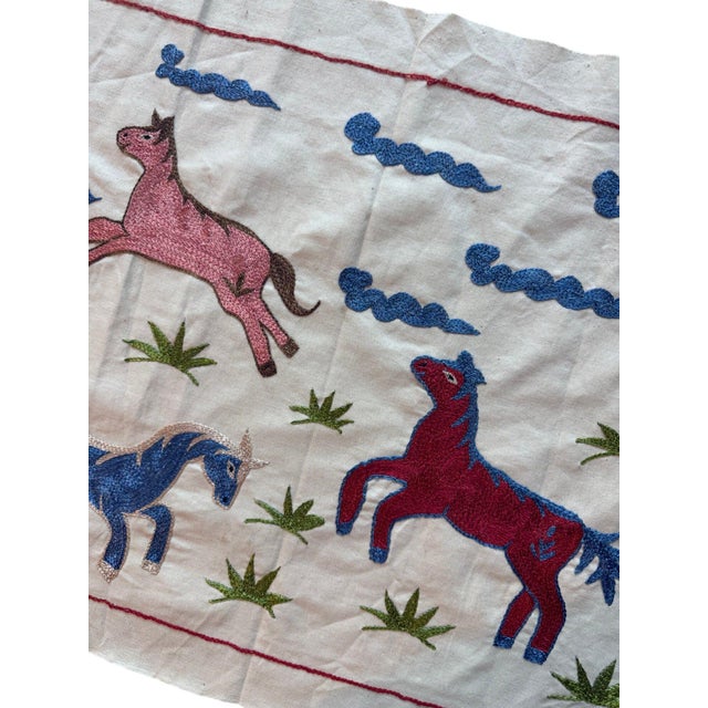 Hand-embroidered Suzani panel from Uzbekistan, worked in fine floss on a cream cotton ground. Six horses move across the...