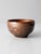 A vintage handmade studio pottery bowl with a richly mottled glaze in warm copper brown, umber, and near-black tones. The...