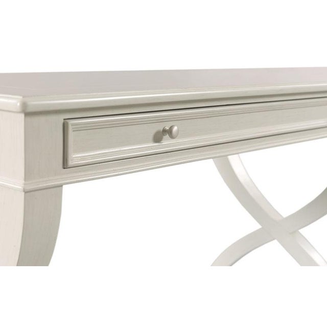 A rectangular top rests over an apron rail drawer flanked by curvaceous intersecting legs. Care Instructions: Wipe with a...