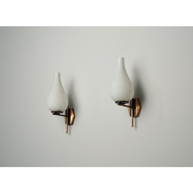 Pair of elegant mid-century modern wall sconces, originating from Italy in the 1960s. Each sconce features a sleek,...