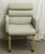 Gray upholstered chair with brass finished metal legs. There is wear and some staining. The manufacturer and exact date of...