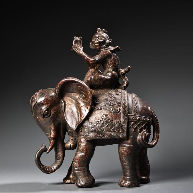 This is a charming antique gilt bronze sculpture depicting a monkey seated atop an elephant, a traditional motif...