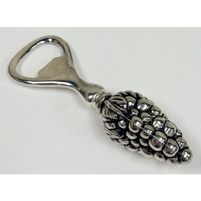 Bottle opener featuring detailed handle shaped like a cluster of grapes and leaves. Heavy metal with silver finish....