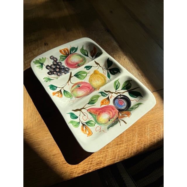 This Italian mid-century piece is a white ceramic serving platter with three compartments, featuring a hand-painted fruit...