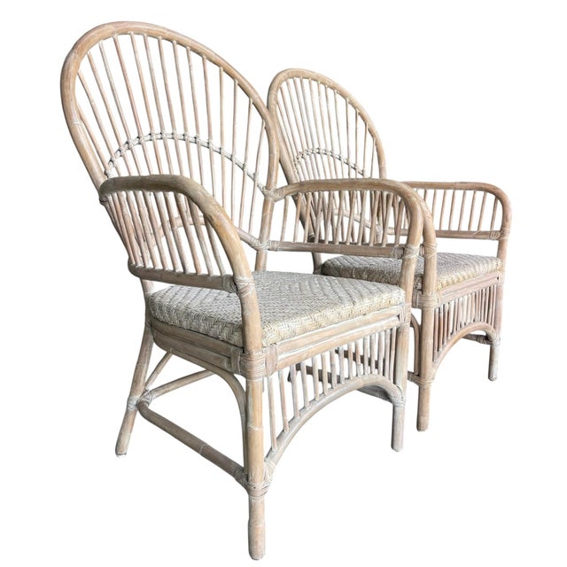 A beautiful pair of rattan armchairs with tall fan backs and a light, sun-washed finish. The airy, sculptural lines give...