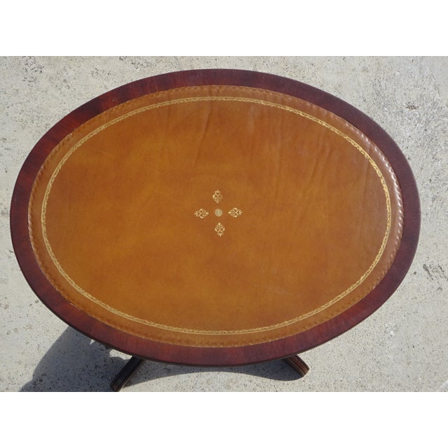 Small side table in solid mahogany with a lovely oval top covered in brown leather with touches of gold. The leather is...