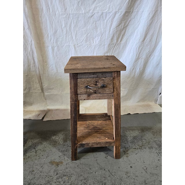 A beautifully handcrafted reclaimed teak side table featuring authentic weathered wood surfaces, dramatic grain texture,...