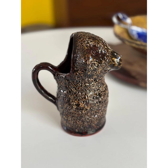 This is a rare, hand sculpted & slipped redware pitcher, depicting a full bodied lamb, made and signed by Ned Foltz. The...