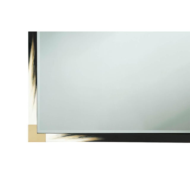 A large modern black lacquered and faux horn mirror, the rectangular top with brass edged corners, enclosing a beveled...